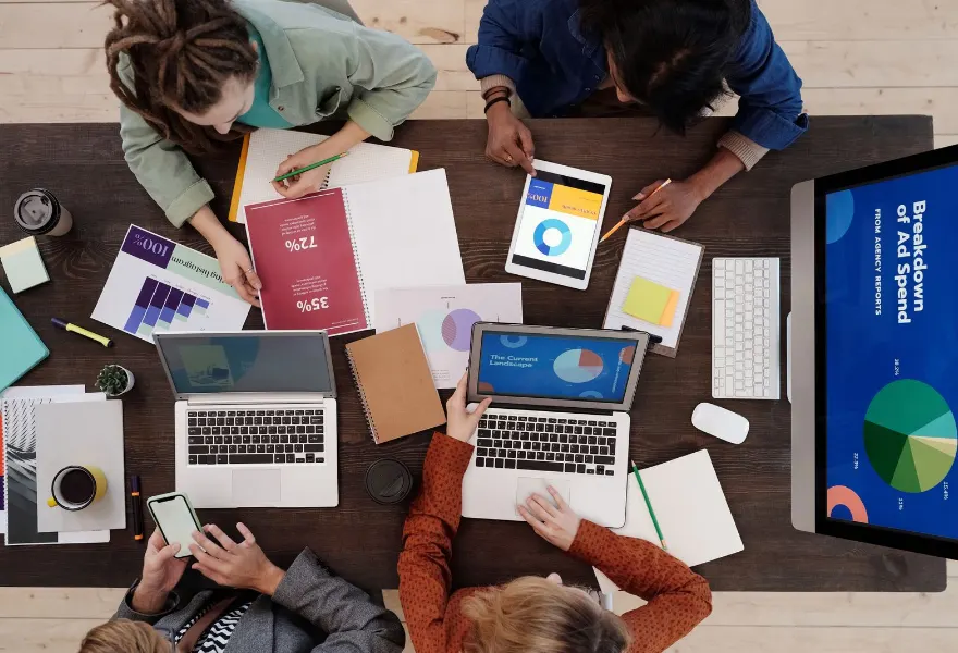 Mesa de trabajo con laptops y material de una campaña digital